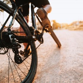 Man feet on bicycle pedal under sunlight on the road - copy space